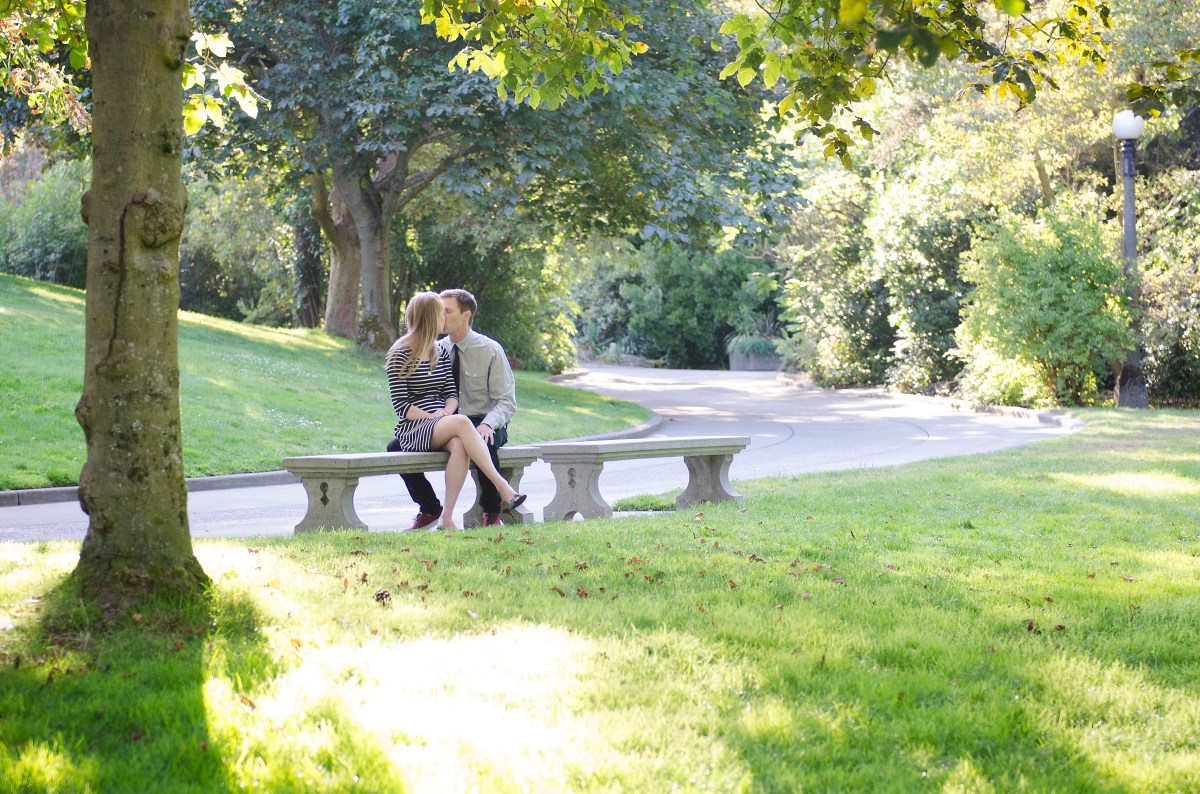 Bri and Ryan kissing on a park bench.